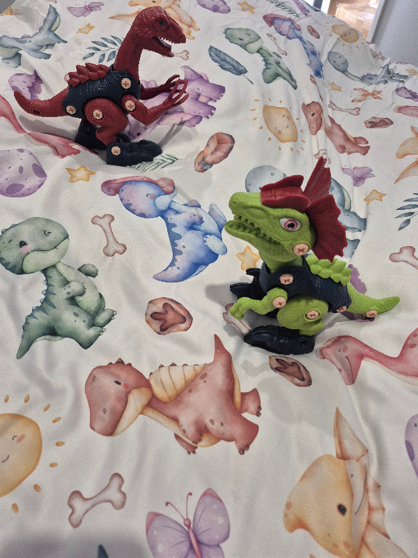 Small toy dinosaurs on a bed with dinosaur themed doona cover