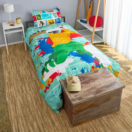 Colorful bedspread with cartoon design of a cricket batter on a bed in a room with a wooden chest and lamp.