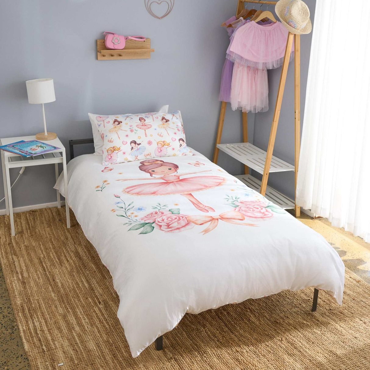 Bedroom with a bed featuring a ballerina design, nightstand, and clothing rack.
