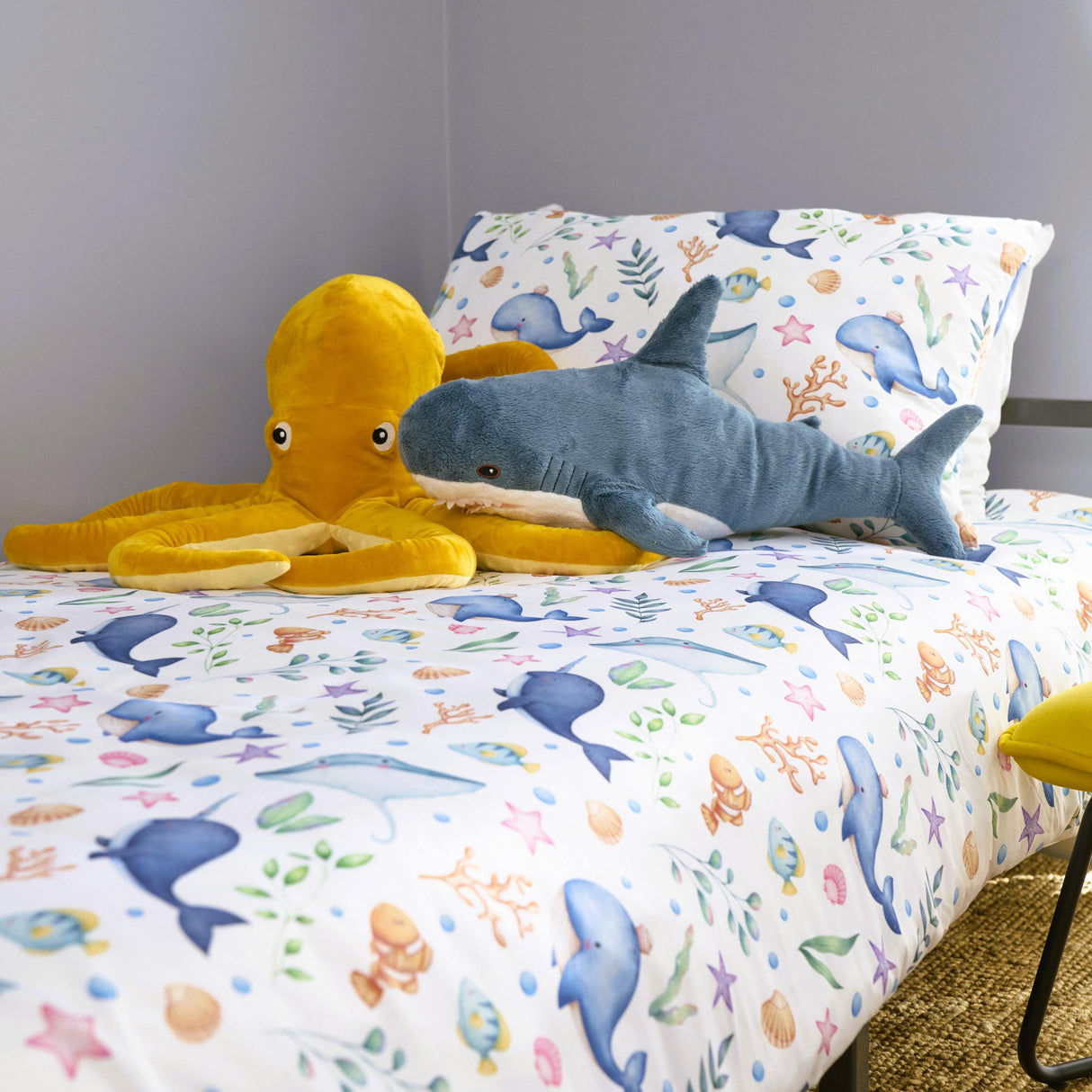 Children's bedding set with ocean-themed design featuring plush toys on a bed.