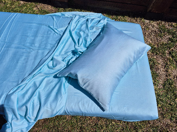 Caribbean blue sheets and pillow on a grassy surface