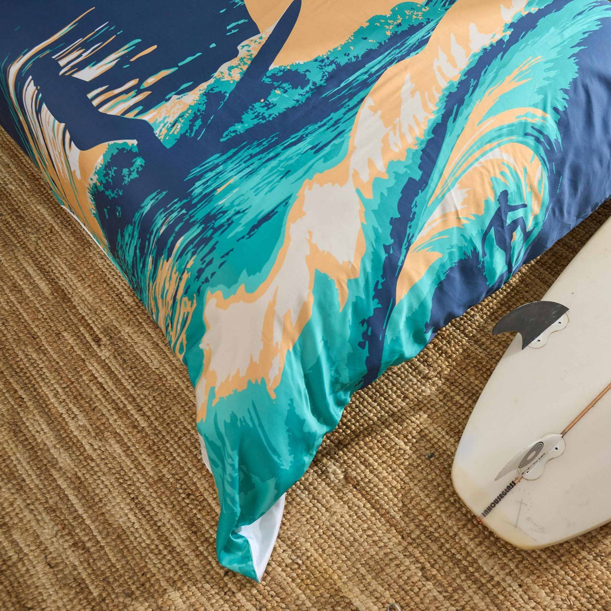 Colorful wave-patterned quilt cover on a woven surface with a surfboard.