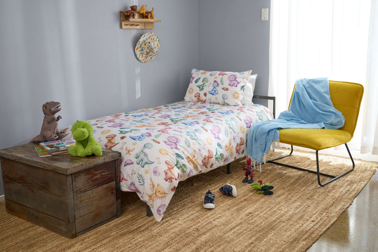 Children's bedroom with dinosaur-themed bedding, toys, and a yellow chair.