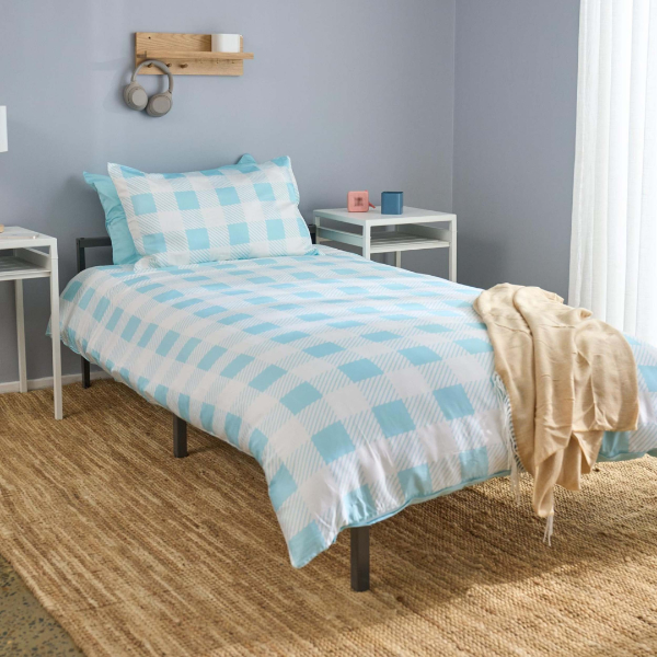 Bed with blue and white checkered bedding in a room with gray walls and wooden flooring.