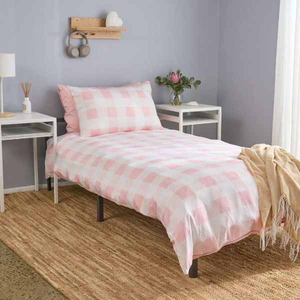 Bedroom with pink checkered bedding and white nightstands.