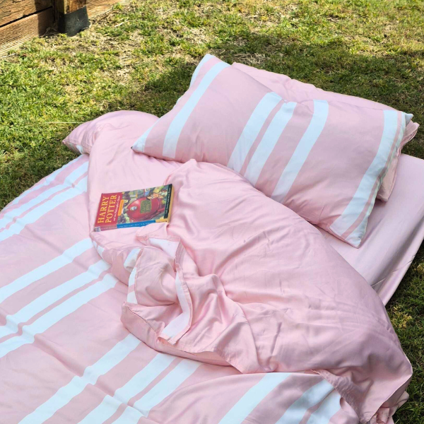 Pink and white striped bedding set on grass