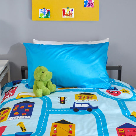 Children's bedroom with a blue pillow and teddy bear on a road-themed bedspread.