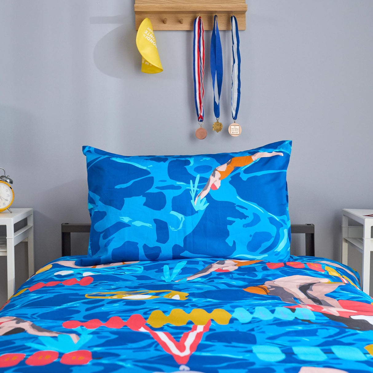 Bedding set with swimmer design on a bed in a room with swimming-themed decor.