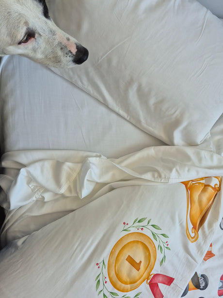 Dog lying on a white pillow and sheet with a colorful quilt cover.