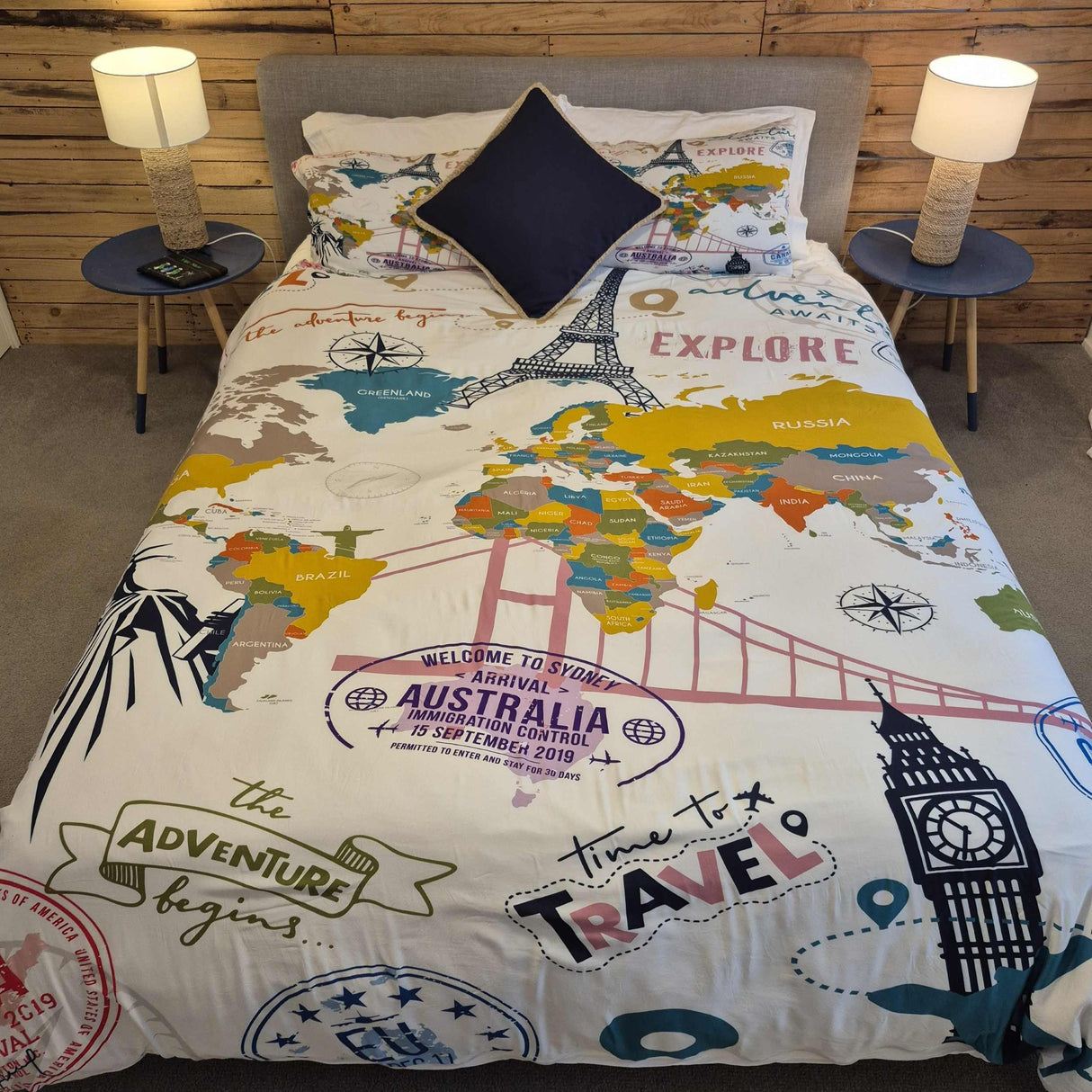 World map-themed bedding set on a bed with decorative pillows in a bedroom setting.
