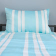 Striped blue and white bedding set on a bed with a gray wall background