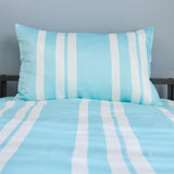 Striped blue and white bedding set on a bed with a gray wall background