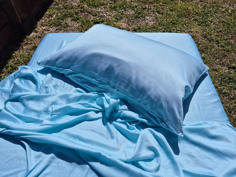 Caribbean blue sheets and pillow on a grassy surface