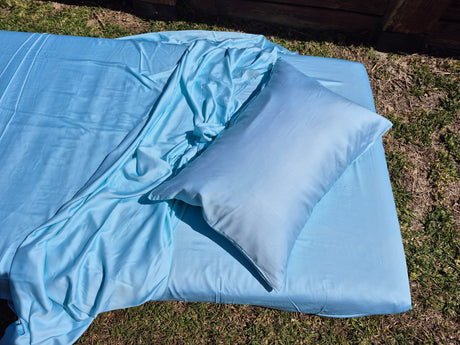 Caribbean blue sheets and pillow on a grassy surface