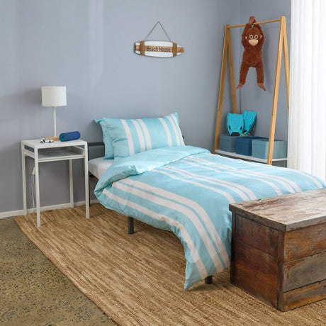 Bedroom with striped bedding, wooden chest, and lamp.