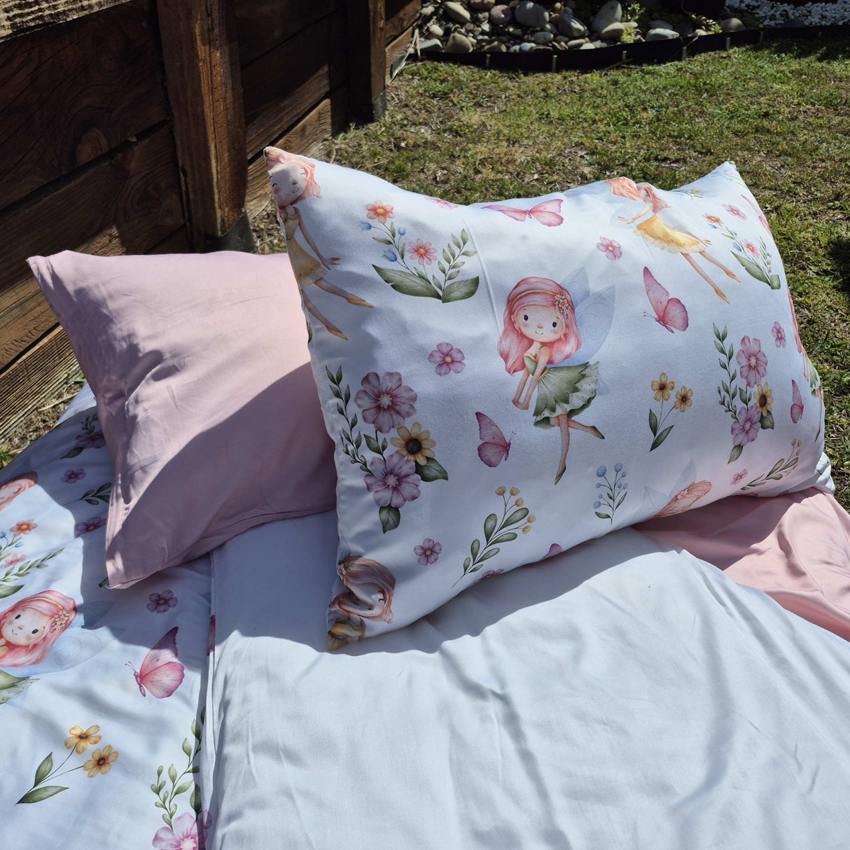 Floral and fairy-themed pillow on a bed outdoors