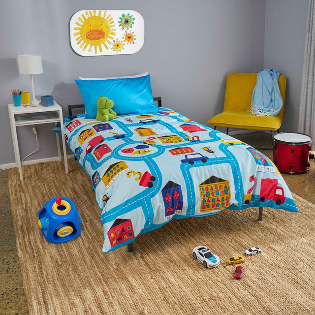 Children's bedroom with colorful bedding featuring vehicles and toys on the floor.