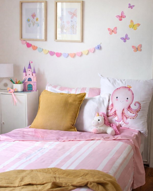Children's bedroom with pink bedding, yellow pillow, and octopus european pillow