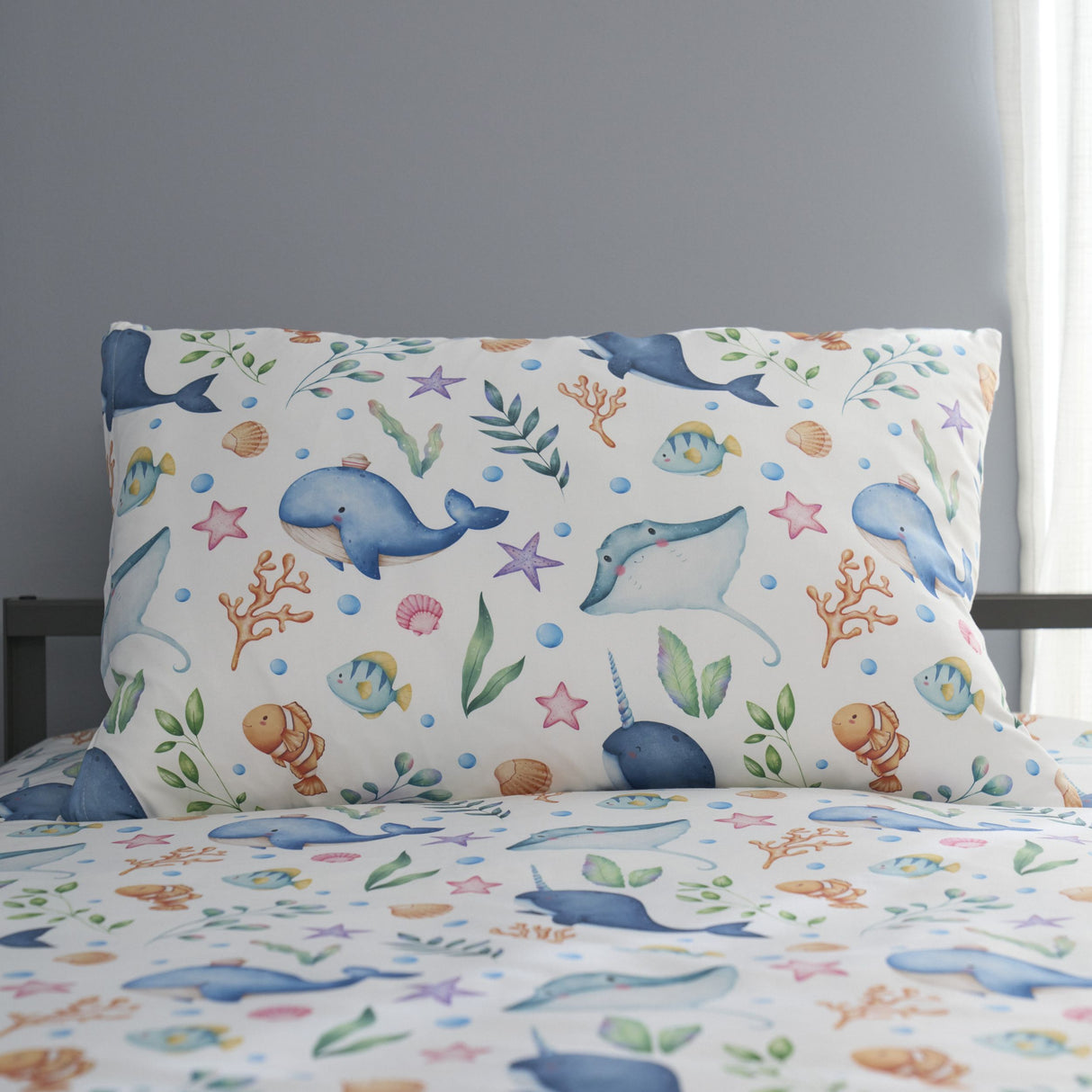 Children's bedding set with ocean-themed design featuring dolphins, fish, and sea plants on a plain background.