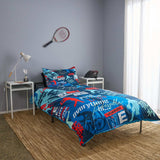 Bedroom with 'Sports Motivation' themed bedding set, tennis racket on wall, and small table with lamp.