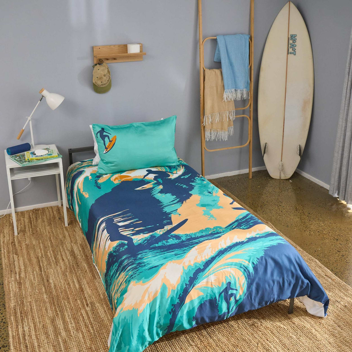 Bedroom with surf-themed bedding and a surfboard against a wall.