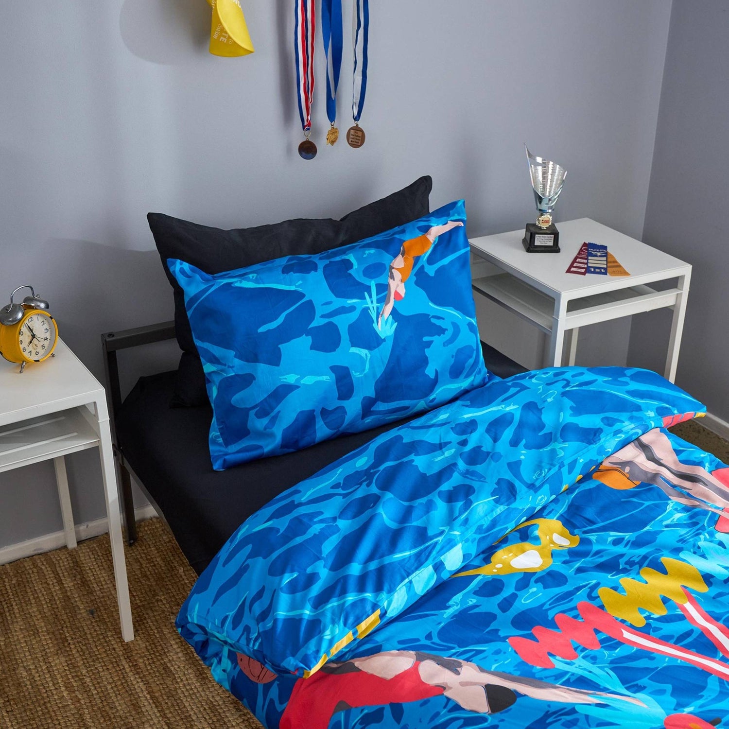 Bedding set with blue water design featuring swimmer graphics in a bedroom setting.
