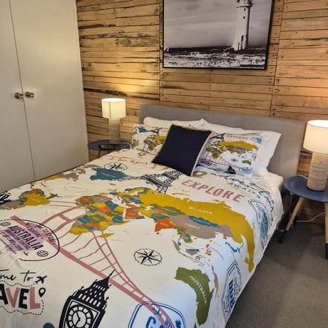 Bedroom with a bed featuring a world map design, wooden wall, and lamp.